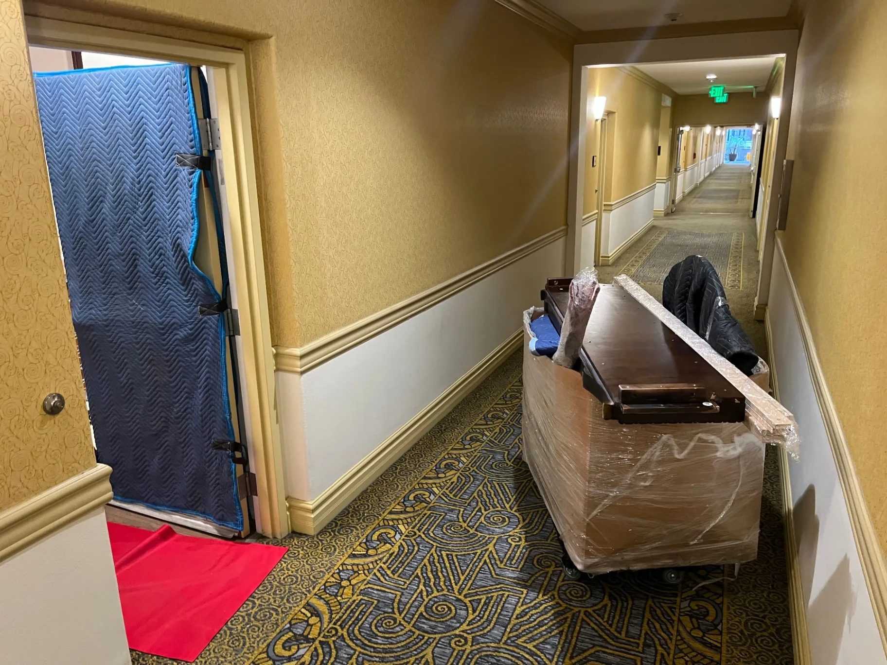 Padded furniture and door protection in an apartment hallway during a Green Echo Movers job