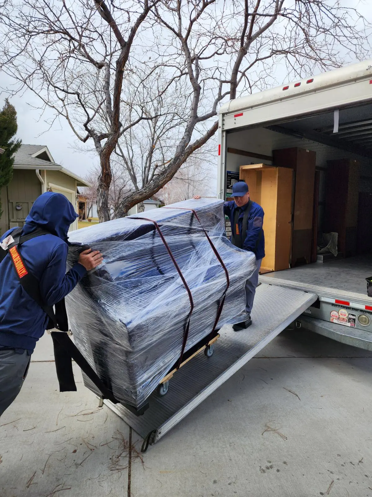 Green Echo movers loading pad-wrapped furniture during a South Orange County move